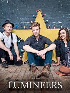 two men and a woman sitting on the floor in front of a wall with a star