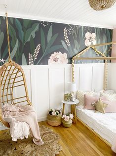 a woman sitting on a chair in a room with flowers painted on the wall behind her