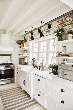 a kitchen with white cabinets and an island in the center, surrounded by potted plants