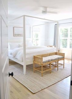 a white bed sitting in a bedroom next to a wooden table and chair on top of a hard wood floor