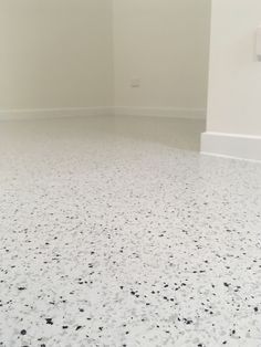 an empty room with white walls and black speckles on the floor is shown