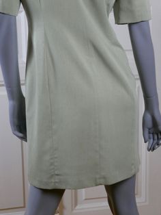 This pale mint green 1990s German vintage dress is the perfect combination of shirt dress and tunic dress. The stunning dress has a notch collar and padded shoulders, and closes in the front to the hip line with 14 material-covered buttons. The dress has a fitted waistline, and features figure-enhancing contour lines on the front and the back. The dress has a tunic-style hemline with two 5-inch (12.7cm) slits in the front, and is lined in a pale green satin acetate fabric. Bust = 38 inches (96cm Pale Green Dress, Pale Mint Green, Acetate Fabric, German Dress, Contour Lines, Summer Tunic, Tunic Shirt Dress, Summer Tunics, Tunic Style