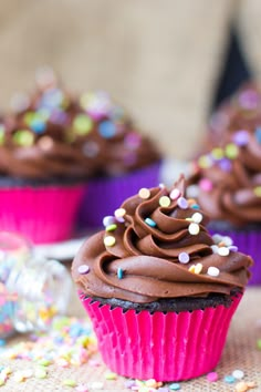 two cupcakes with chocolate frosting and sprinkles on a table