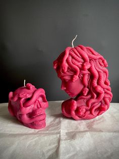 two pink candles sitting next to each other on top of a white sheeted table