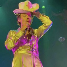 a man with a cowboy hat on his head singing into a microphone at a concert