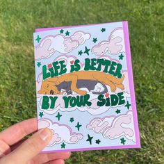 someone holding up a card that says life is better by your side on the grass