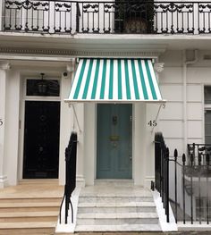 a green and white striped awning in front of a building with black wrought iron railings