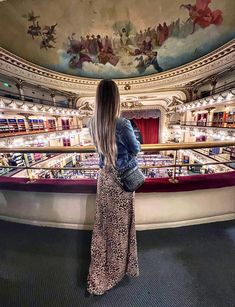 a woman standing in front of an auditorium looking down at the stage and seating area