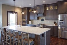 a large kitchen with an island in the middle and lots of chairs at the counter