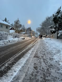 two people walk down a snowy street at night in the winter, with snow on the ground