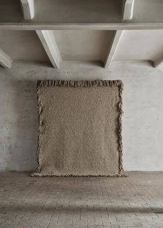 an empty room with a rug hanging from the ceiling and brick flooring on the walls