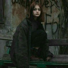 a woman sitting on top of a wooden bench