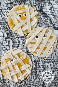 two pies with faces made out of them on top of a mesh table cloth