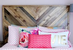 a bed topped with lots of pillows next to a headboard made out of wood