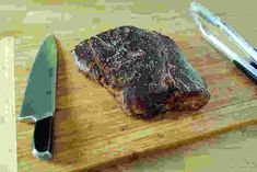 a steak on a cutting board next to a knife