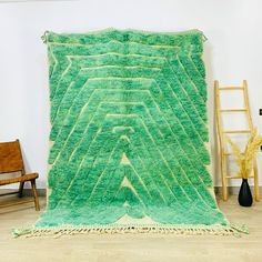 a large green rug is on the floor in front of a chair and ladders