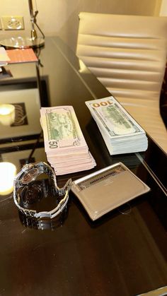 a table topped with money sitting next to a watch on top of a wooden desk