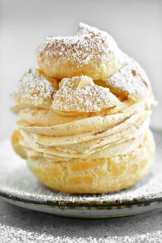 a stack of powdered sugar covered doughnuts on a silver plate with sprinkles