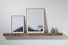 three framed photographs on a wooden shelf