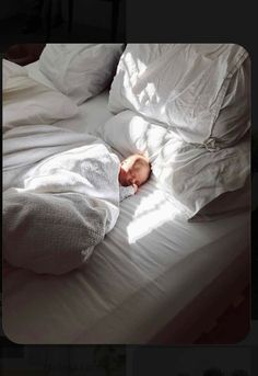 a baby is sleeping on a bed with white sheets