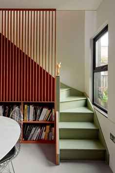 there is a book shelf with books on it next to the stairs in this room