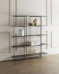 a shelf with books, vases and other items on it in a white room