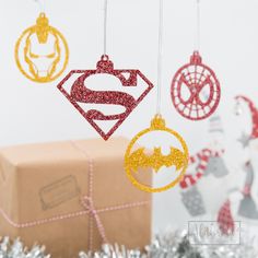 some ornaments are hanging from strings near a present box and tinsel garlands on the table