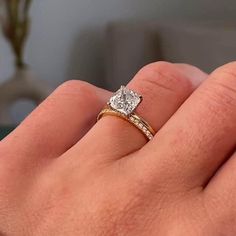 a person's hand holding a diamond ring in their left hand, with the engagement band on