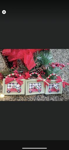 three boxes with christmas decorations on them sitting in front of some pine cones and red bows