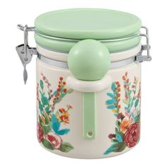 a green lidded jar with flowers painted on it and a handle to the top