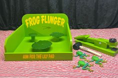 the frog flinger is set up on top of a striped tablecloth with other toys