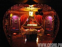 an elaborately decorated stage set up for a wedding reception with red drapes and gold accents