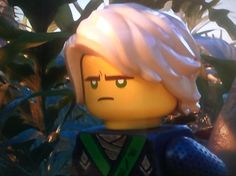 the lego movie character is standing in front of some plants and looking into the distance