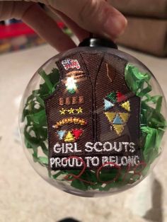 someone is holding up a christmas ornament that says girl scouts proud to belong