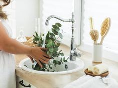 a woman is washing plants in the sink