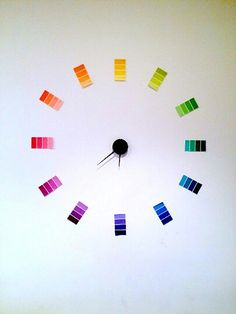 a clock made out of colored swatches on a white wall with the numbers painted in different colors