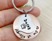 a person holding a metal keychain that says, always in my heart on it