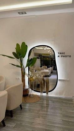 there are two chairs and a plant in front of the mirror that says take a photo