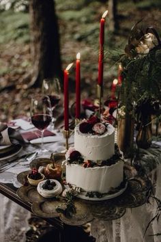 a white cake sitting on top of a table covered in candles and plates filled with food