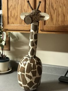 a giraffe statue sitting on top of a counter next to a potted plant