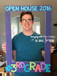 a man holding up a photo frame with the words 3rd grade written in front of him