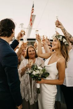 a bride and groom toasting with their guests on the deck of a boat in front of an american flag