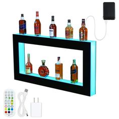 an illuminated shelf with liquor bottles and remotes on it next to a wall charger