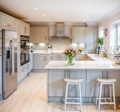 a large kitchen with two stools in front of the center island and an oven