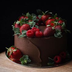 a chocolate cake with strawberries and leaves on the top is ready to be eaten