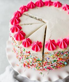 a white cake with pink icing and sprinkles on it's side