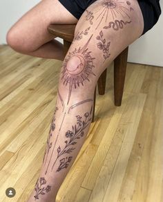 a person with tattoos on their legs sitting on a wooden floor next to a chair