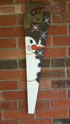 a snowman is hanging on the side of a brick wall