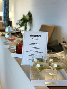 two glasses of wine are sitting on a counter with a sign in front of them