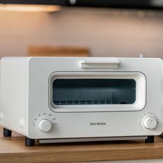 a white toaster oven sitting on top of a wooden counter next to a microwave